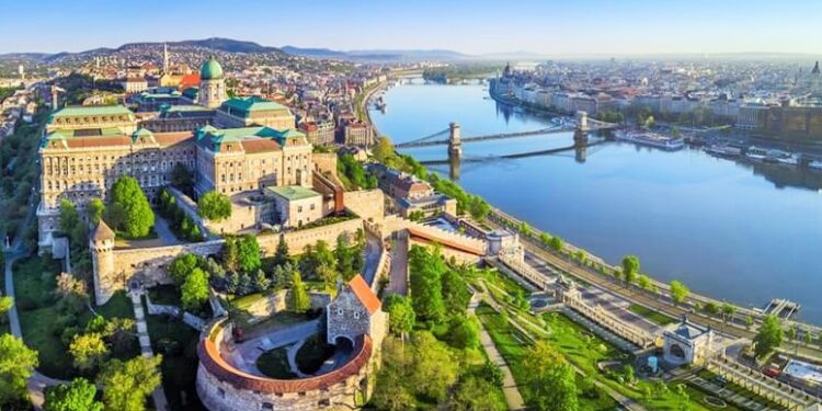 Budapest, Hungary - Aerial panoramic skyline view of Buda Castle Royal Palace with Szechenyi Chain Bridge, St.Stephen's Basilica, Hungarian Parliament and Matthias Church at sunrise with blue sky; Shutterstock ID 1078814498; Purchase Order: site; Job: ; Client/Licensee: ; Other: