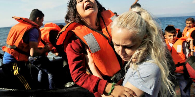 A Syrian girl reacts as she helped by a volunteer upon her Oct. 9 arrival from Turkey to the Greek island of Lesbos. Greece is bracing for thousands more Syrian and other migrants to land on Lesbos and other key island crossings from Turkey, as those fleeing conflict remain undeterred by the worsening weather and colder autumn temperatures. (CNS photo/Yannis Kolesidis, EPA) See GREECE-MIGRANTS-HELP Oct. 13, 2015.