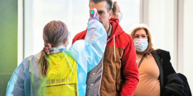 Passengers arriving from Melbourne are greeted by staff from NSW Health to check for COVID-19 symptoms at Sydney Airport, Thursday, July 2, 2020. Suburbs in Victoria that have seen soaring cases of coronavirus will be locked down until July 29. (AAP Image/James Gourley) NO ARCHIVING