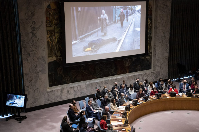 Images from devastation in Ukraine are displayed during a meeting of the UN Security Council, Tuesday, April 5, 2022, at United Nations headquarters. Ukrainian President Volodymyr Zelenskyy addressed the U.N. Security Council for the first time Tuesday at a meeting focused on what appears to be widespread deliberate killings of civilians by Russian troops. Videos of streets in the town of Bucha outside Kyiv strewn with corpses have sparked global outrage and vehement denials from the Russian government that it was responsible. (AP Photo/John Minchillo)