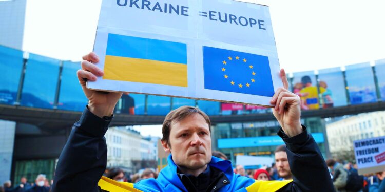 BRUSSELS, BELGIUM - MARCH 01: A man holds a banner during a gathering with President of the European Parliament (EP), Roberta Metsol, EP members and Ukrainians for a demonstration in front of the European Parliament after a special plenary session on the Russian invasion of Ukraine at the EU headquarters in Brussels on March 01, 2022. (Photo by Dursun Aydemir/Anadolu Agency via Getty Images)