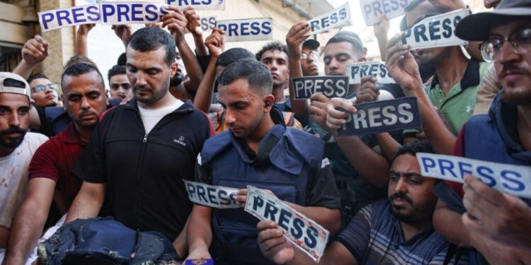 Mourners and colleagues holding 'press' signs surround the body of Al-Jazeera Arabic journalist Ismail al-Ghoul, killed along with his cameraman Rami al-Refee in an Israeli strike during their coverage of Gaza's Al-Shati refugee camp, on July 31, 2024. - Al Jazeera condemned the killing of two of its journalists, calling the deaths a "cold-blooded assassination" in a statement. (Photo by Omar AL-QATTAA / AFP)