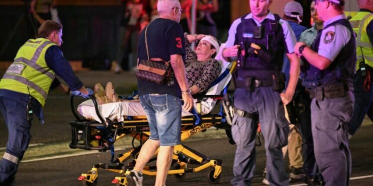 Health workers move a woman on a stretcher to an ambulance after a shooting incident at Bondi Beach in Sydney on December 14, 2025. Australian police said two people were in custody following reports of multiple gunshots on December 14 at Sydney's famed Bondi Beach, urging the public to take shelter. (Photo by Saeed KHAN / AFP)